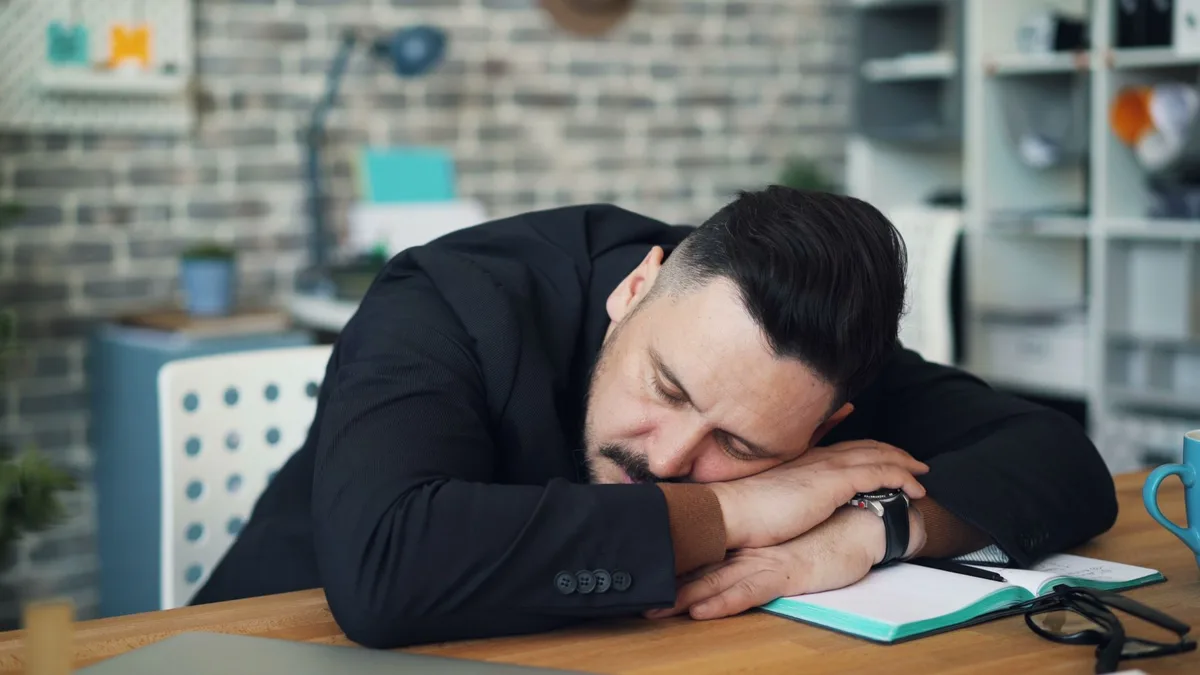 Personne allongée au lit, l'air fatiguée et épuisée au réveil