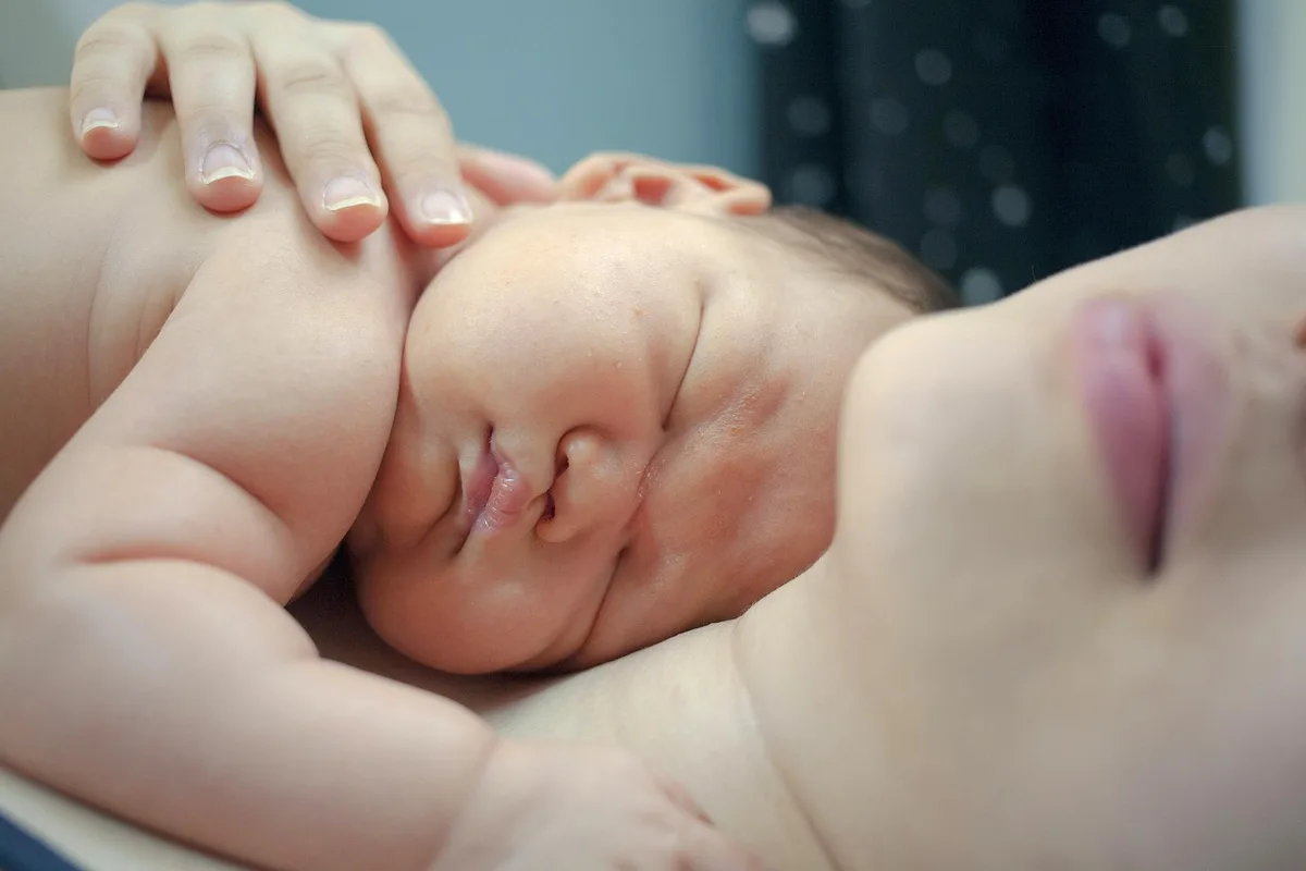 Parents nettoyant doucement les fesses d'un bébé avant d'appliquer une crème barrière