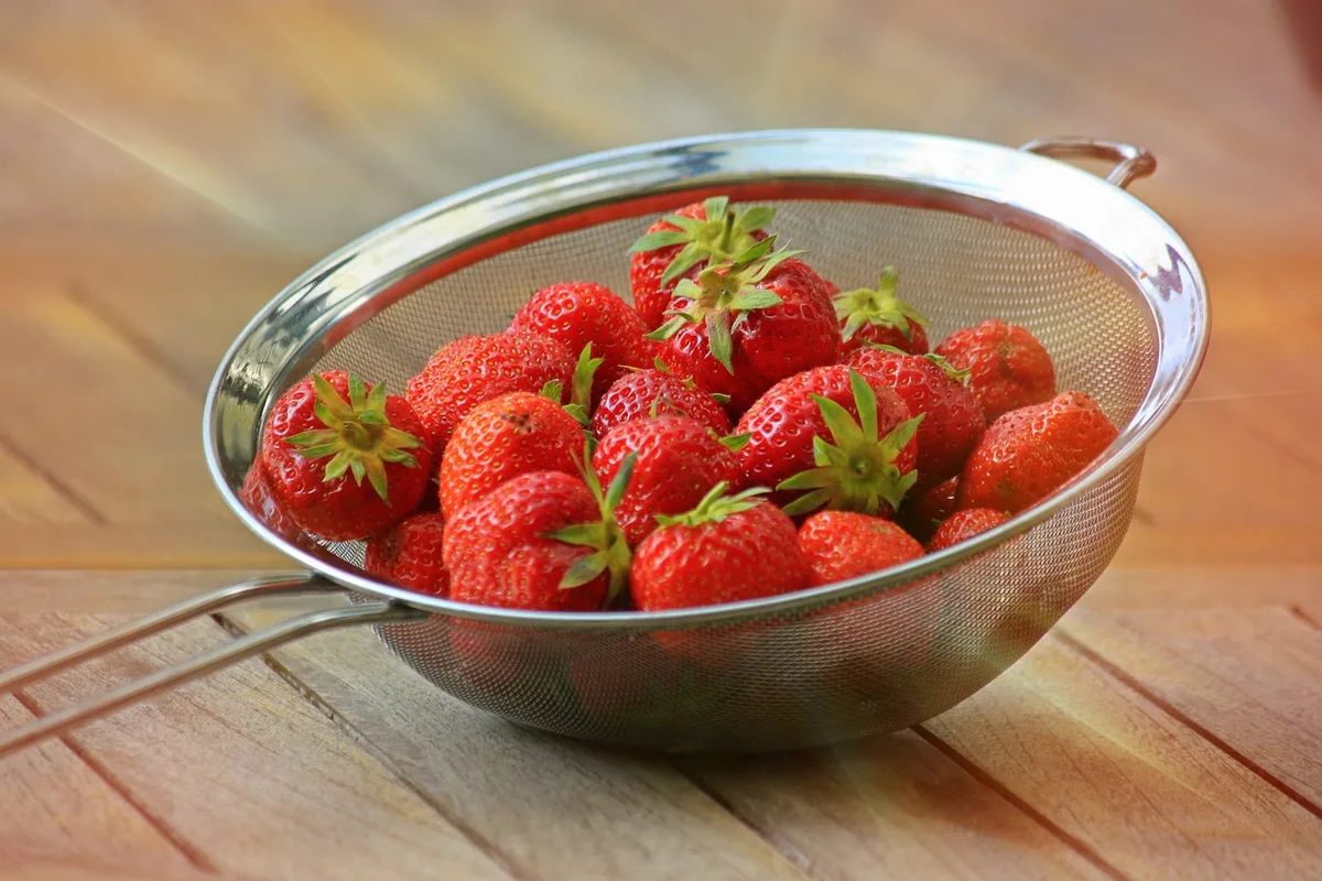 Femme buvant un verre d'eau à côté d'un bol de fruits et de céréales complètes